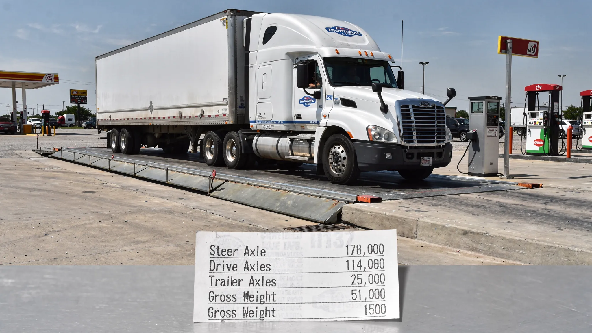 A tractor-trailer on a certified truck scale with a printed weight ticket nearby, showing steer axle, drive axles, and trailer axles weights, in a realistic truck stop setting.